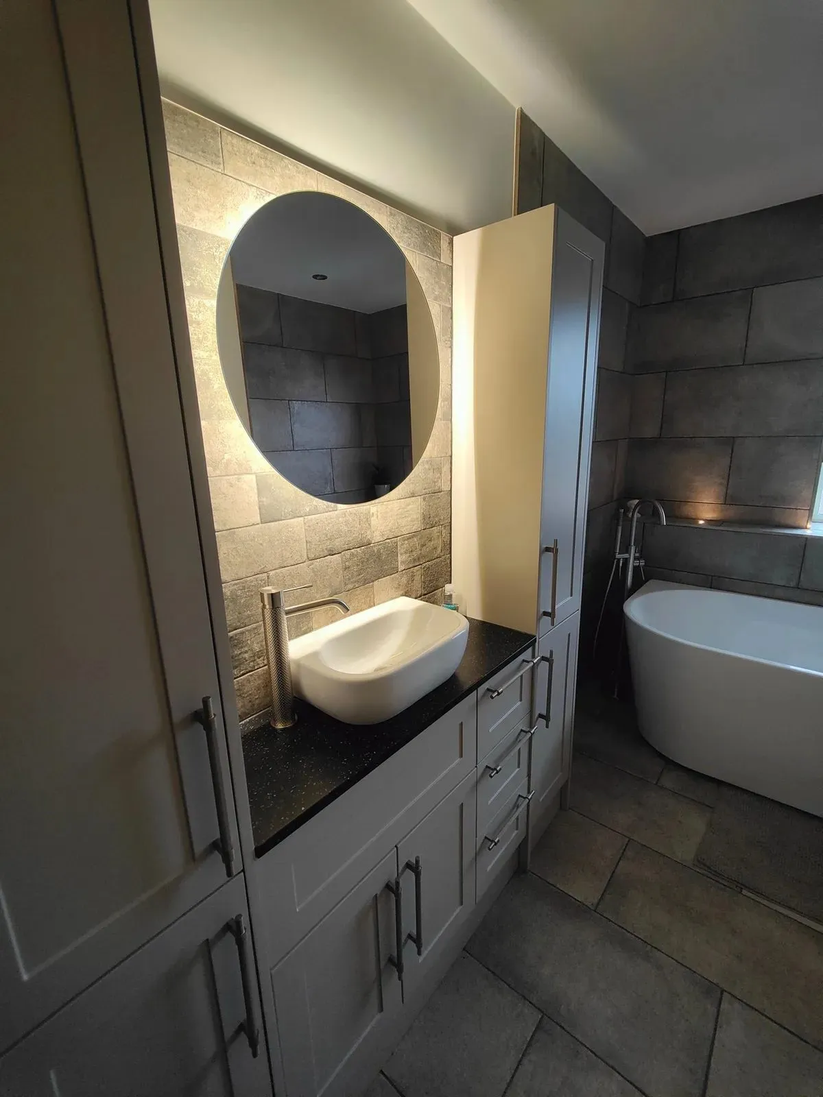 Modern bathroom renovation with round LED mirror, floating basin and freestanding bath